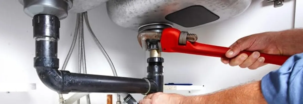 Garbage disposal repair technician tightening the sink drain and disposal connection in Long Beach, CA