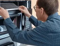 Appliance repair technician replacing a microwave vent filter in Long Beach, CA