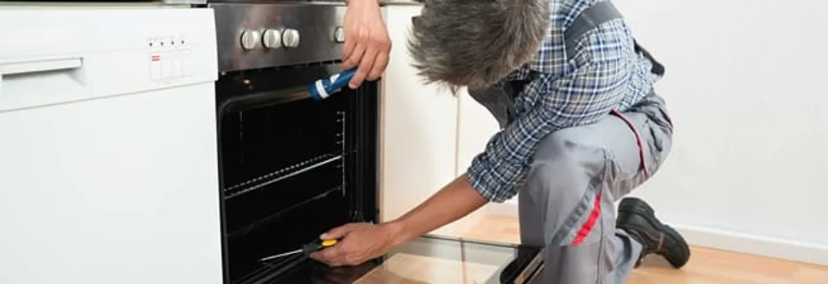 Oven repair technician inspecting and servicing an electric oven in Long Beach, CA
