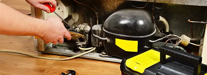 Refrigerator repair technician fixing the compressor and wiring in Long Beach, CA